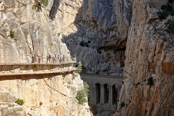 Grupo de visitantes con casco recorriendo la pasarela colgada de la pared del cañón
